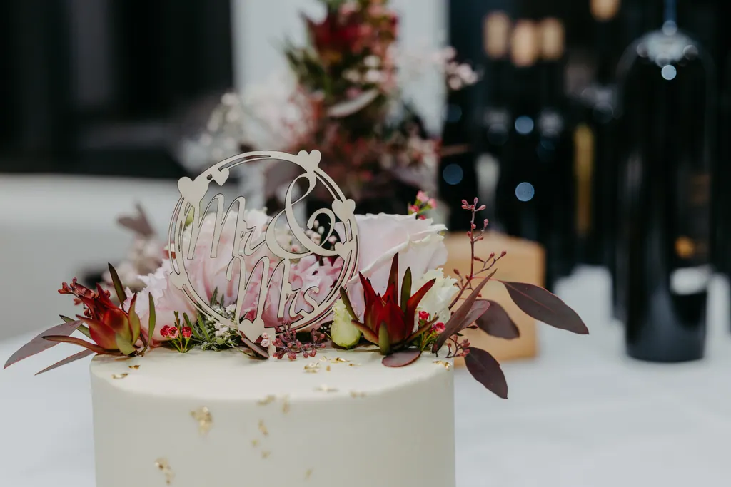 Weiße Hochzeitstorte mit Blüten und filigranem Tortenaufsatz