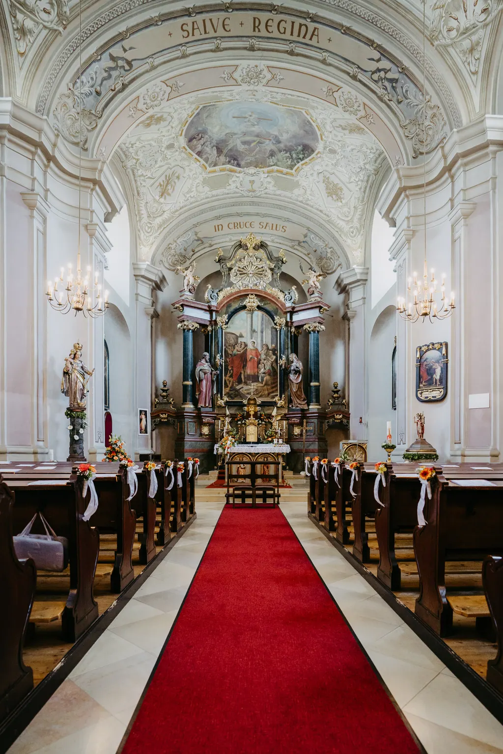 Barocker Kirchenraum mit rotem Teppich und geschmückten Bänken