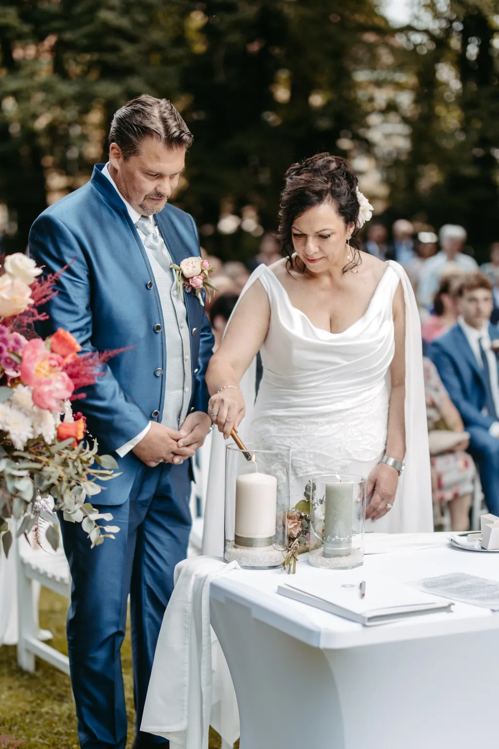 Brautpaar entzündet am Trautisch im Freien gemeinsam die Hochzeitskerze