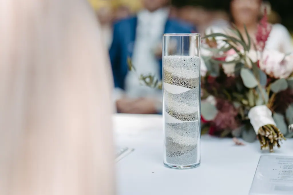 Glasvase mit geschichtetem Sand vom Sandritual auf dem Trautisch