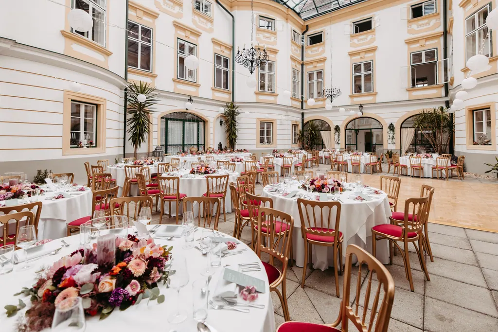 Festlich gedeckte runde Tafeln mit Blumen im Innenhof des Schlosses