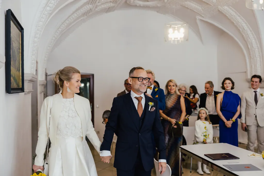 Brautpaar betritt Hand in Hand den hellen Trausaal mit Gewölbedecke