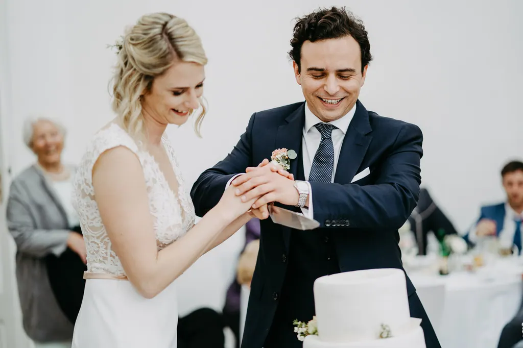 Brautpaar schneidet gemeinsam die Hochzeitstorte an