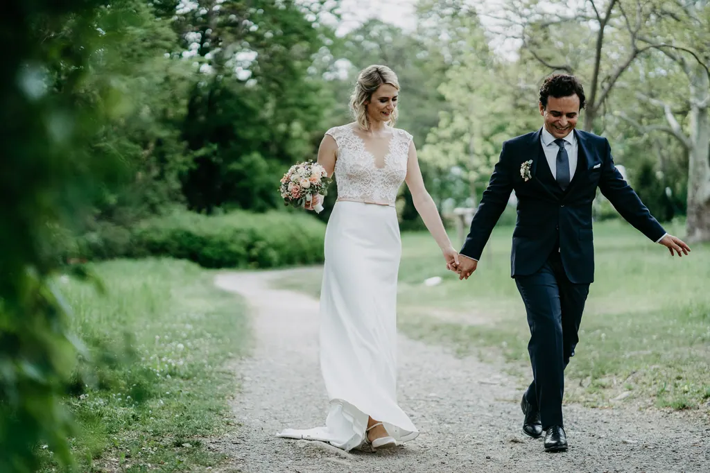 Brautpaar geht Hand in Hand über einen Kiesweg im Schlosspark