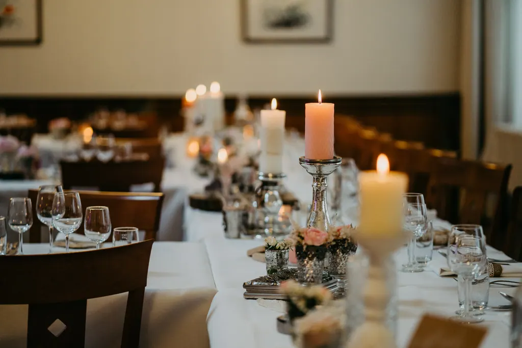 Lange gedeckte Tafel mit Kerzen in der holzvertäfelten Gaststube