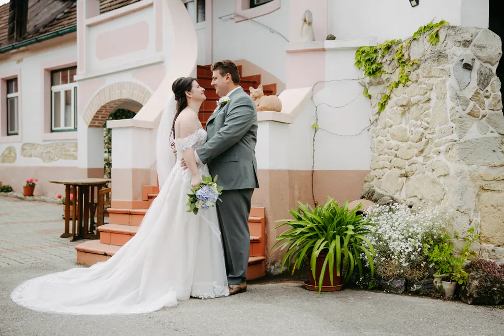 Brautpaar vor einem rosa Winzerhaus mit Freitreppe und Steinmauer