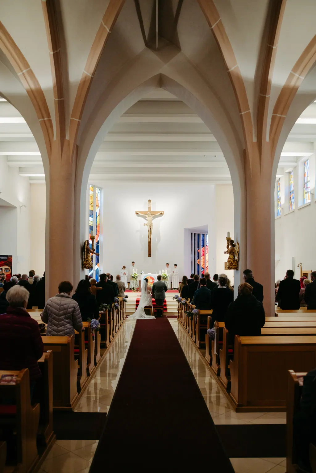 Blick durch den Mittelgang der Kirche mit Spitzbögen zum Altar