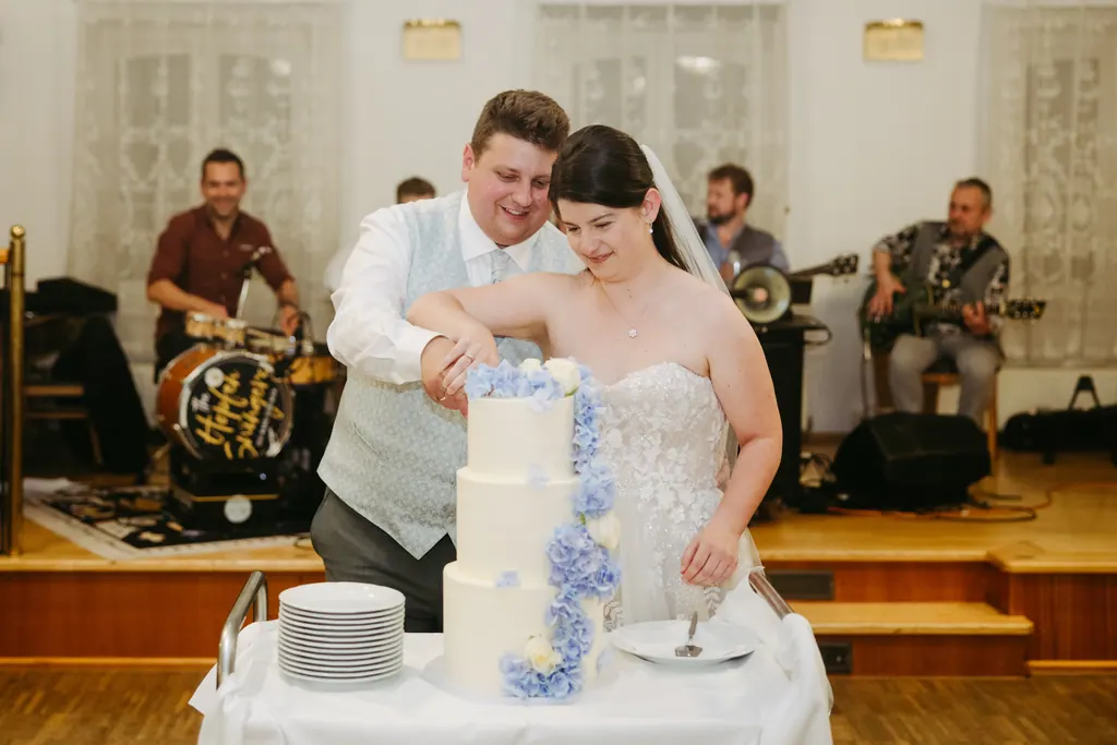 Brautpaar schneidet die Torte mit blauen Hortensienblüten an
