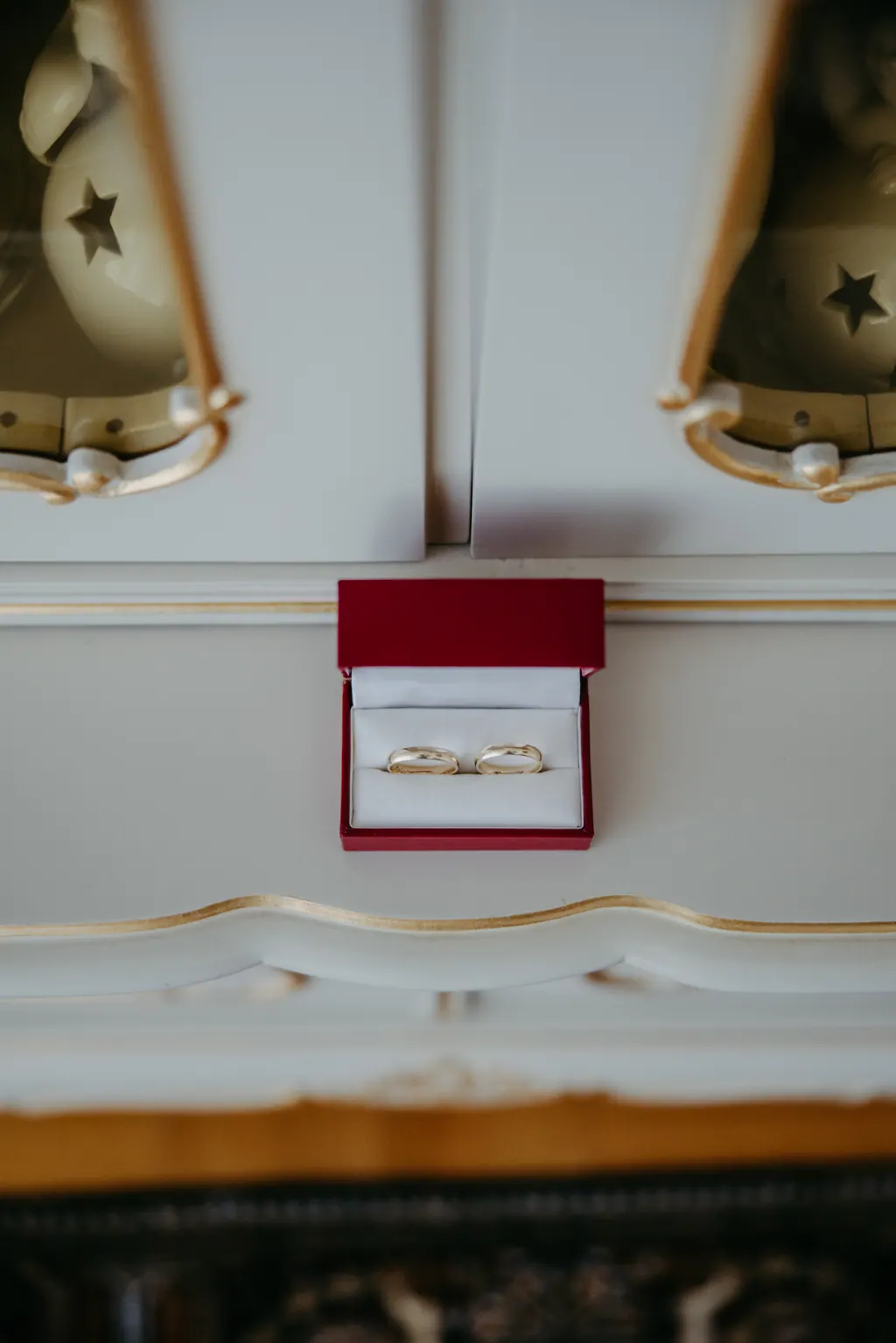 Rotes Ringkästchen mit Eheringen auf einer weißen Kommode mit Goldrand