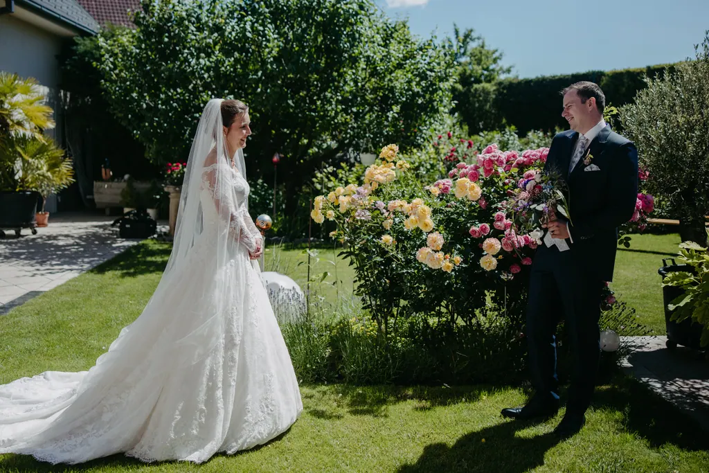 Braut und Bräutigam begegnen sich im Garten neben blühenden Rosen
