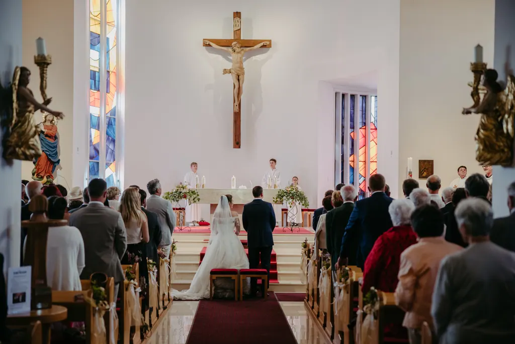 Blick durch den Mittelgang der hellen Kirche zum Brautpaar vor dem Altar