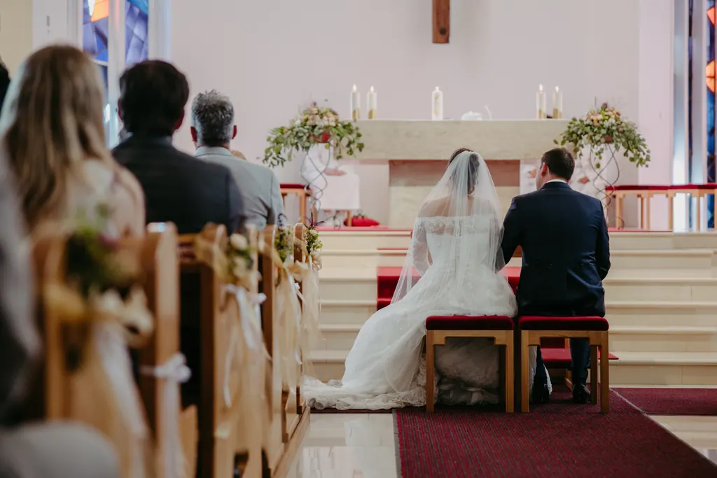 Brautpaar sitzt von hinten gesehen vor dem geschmückten Altar