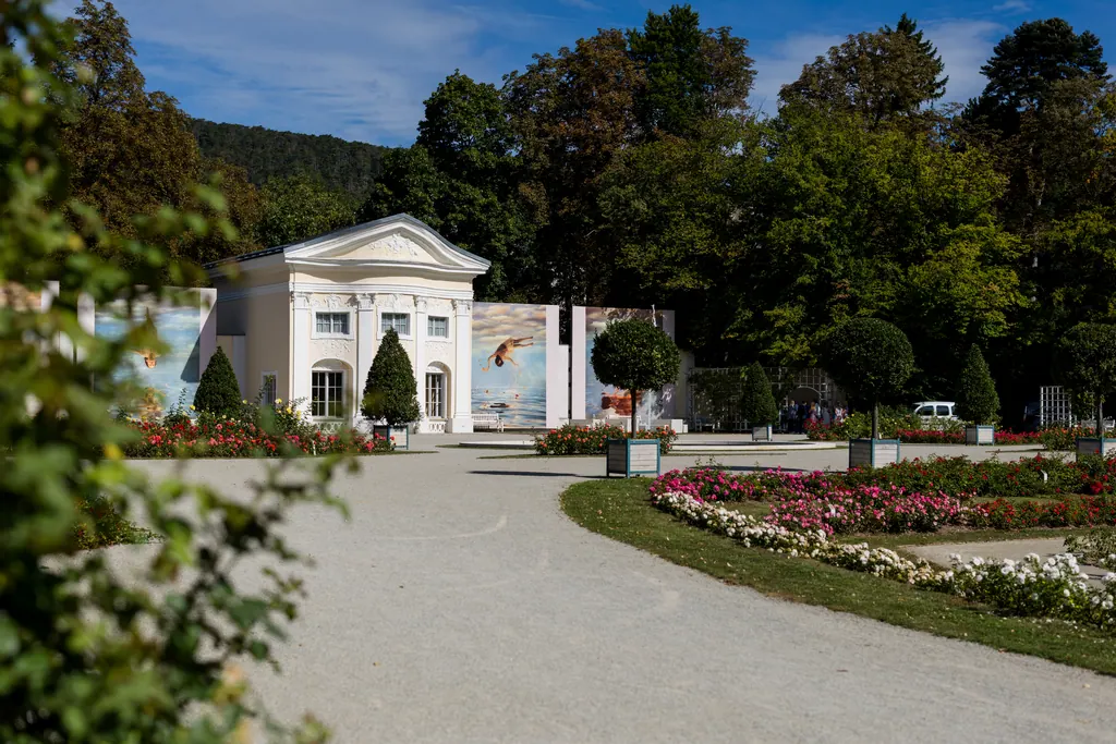 Geschwungener Weg durch das Rosarium mit blühenden Rosen vor der barocken Orangerie