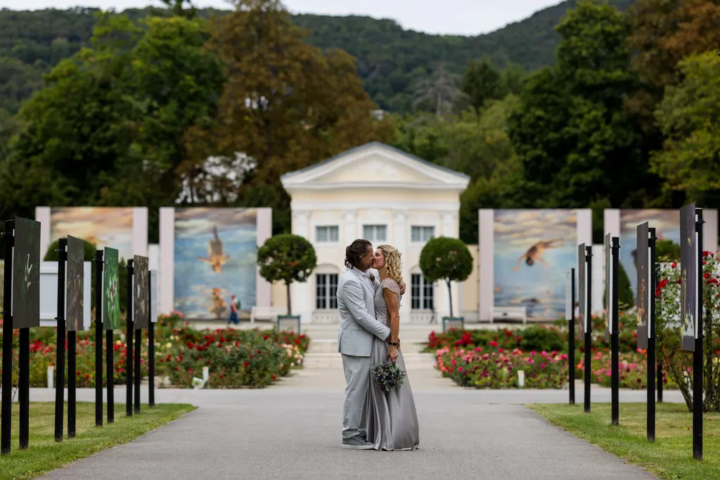 Brautpaar küsst sich auf der Mittelachse des Rosariums vor der Orangerie
